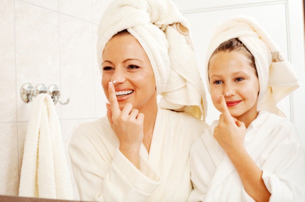 Mother and daughter are putting on face cream.