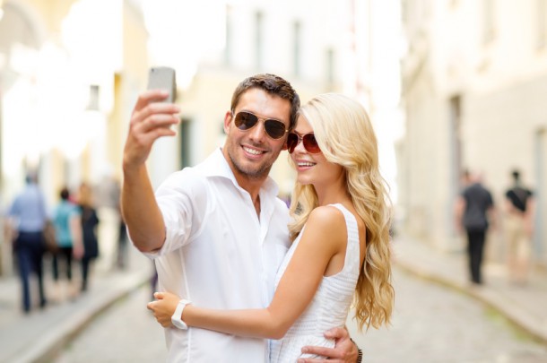 smiling couple with smartphone in the city