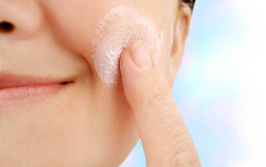 caucasian smiling woman applies moisturizer onto face